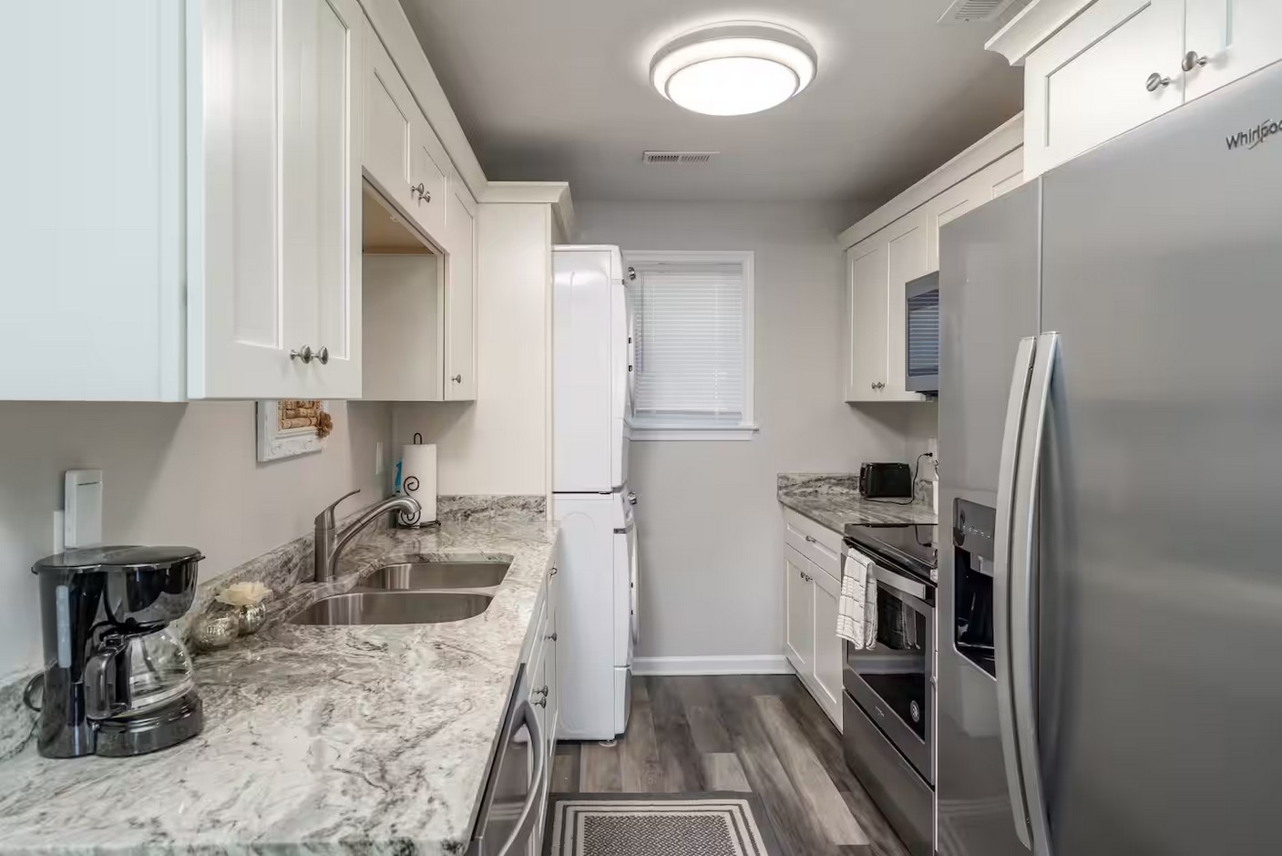 Fully equipped kitchen with stainless steel appliances, white cabinets, and granite countertops.