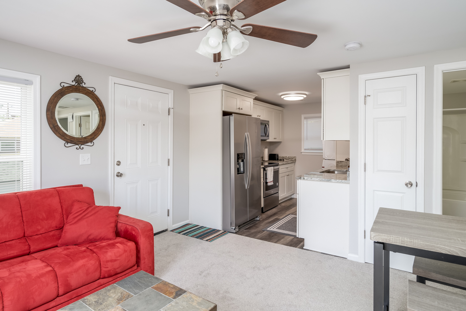 Cozy living room with a red couch, ceiling fan, and open kitchen layout.
