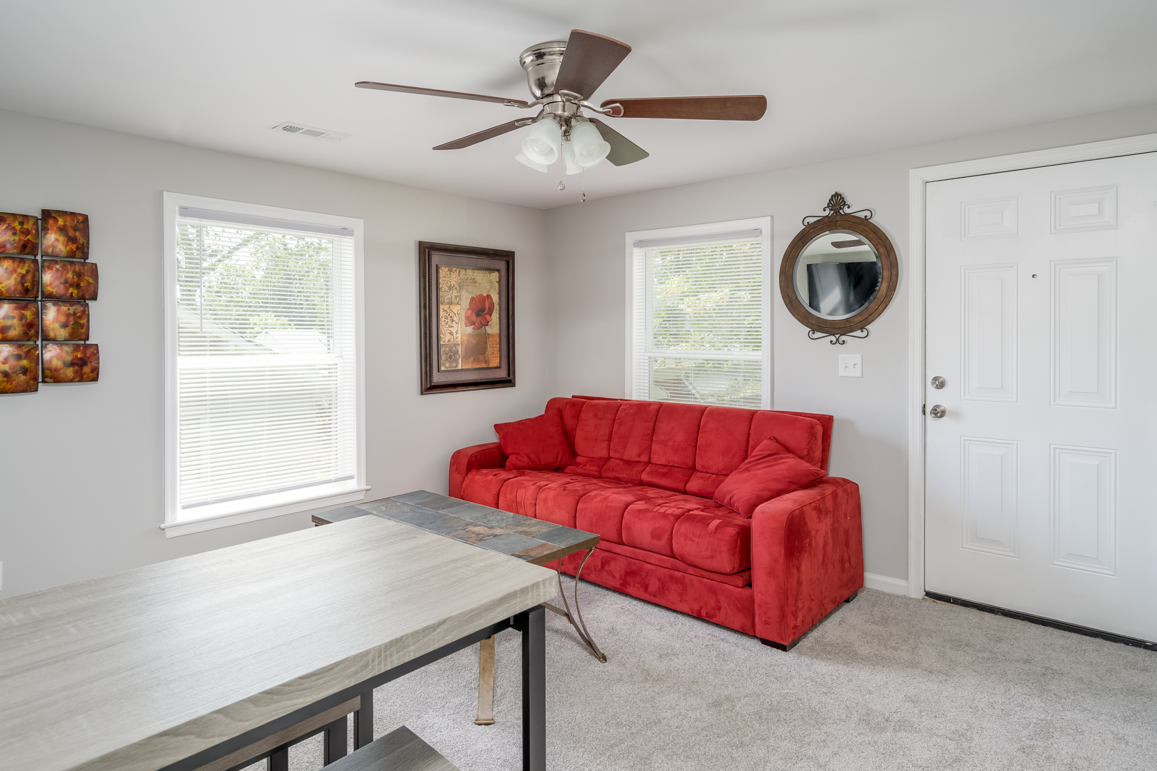 Bright and inviting living area with a red couch, dining table, and modern decor.