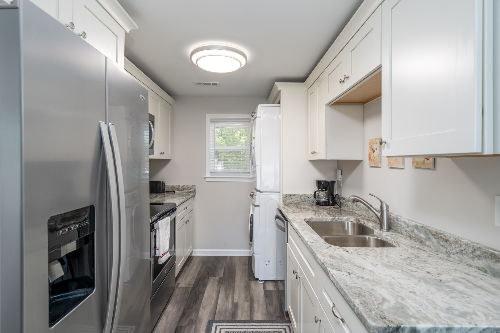 Modern kitchen with white cabinetry, stainless steel appliances, and a washer-dryer unit.