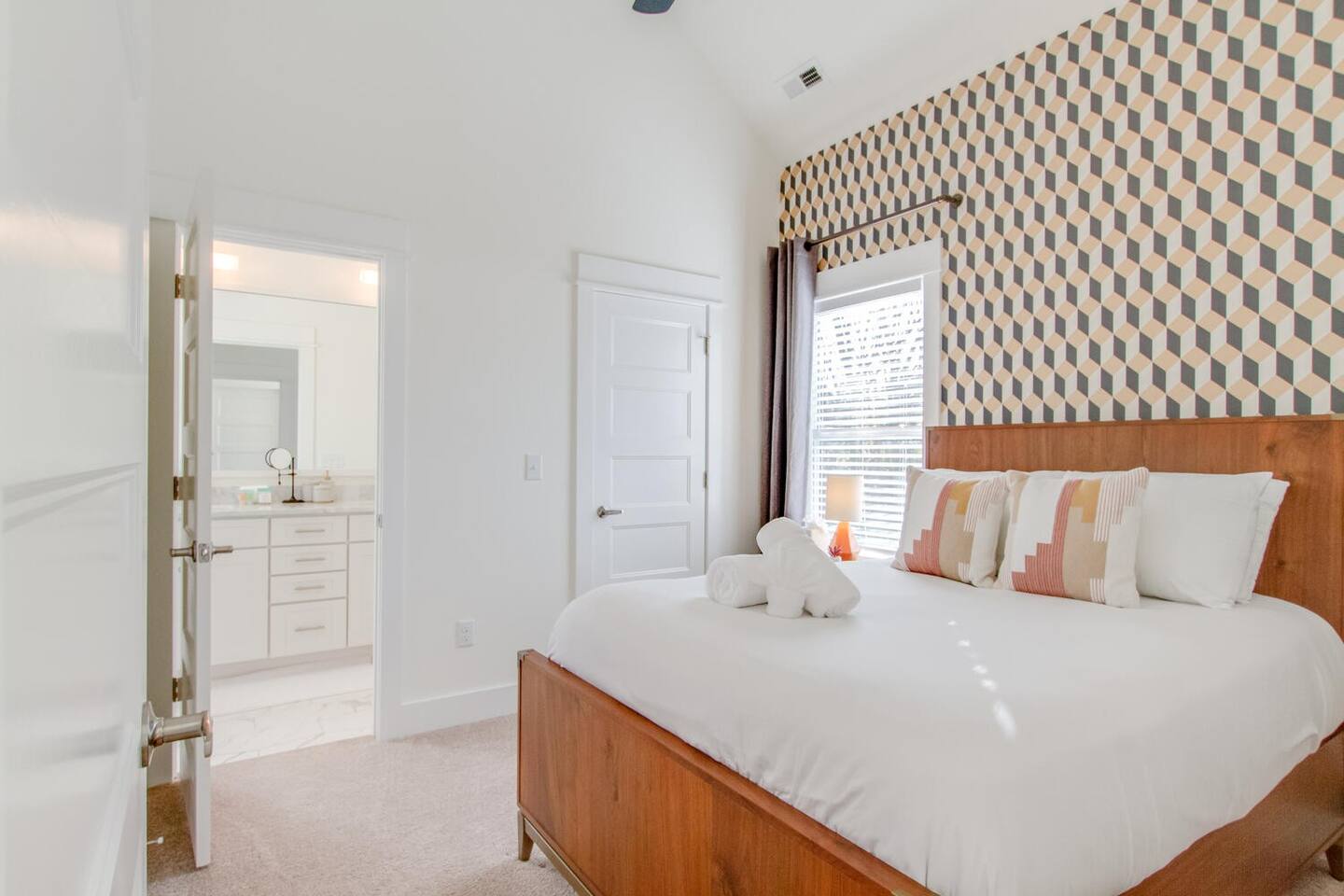 Spacious bedroom with geometric wallpaper and soft lighting