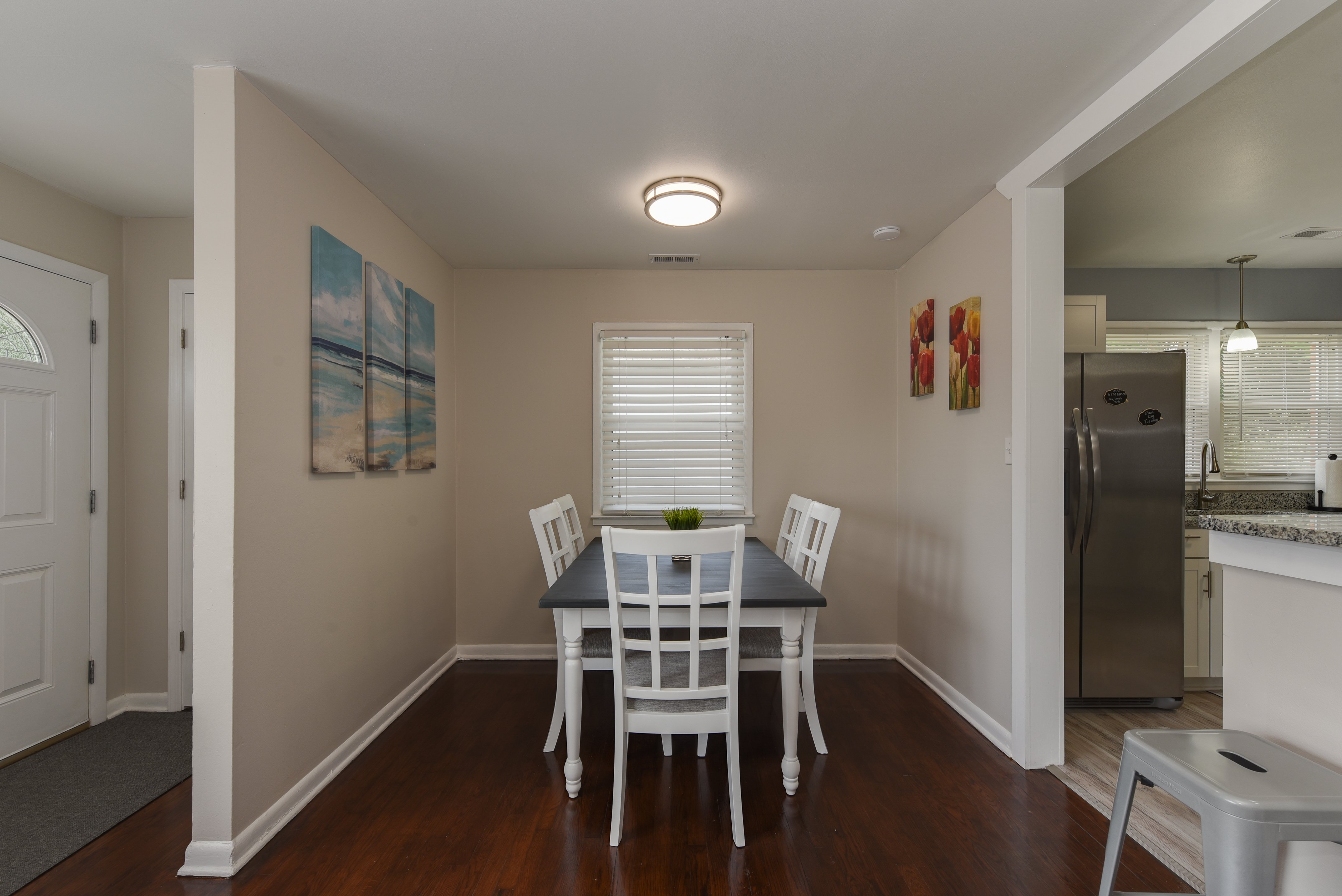 Dining area with white table set and coastal artwork