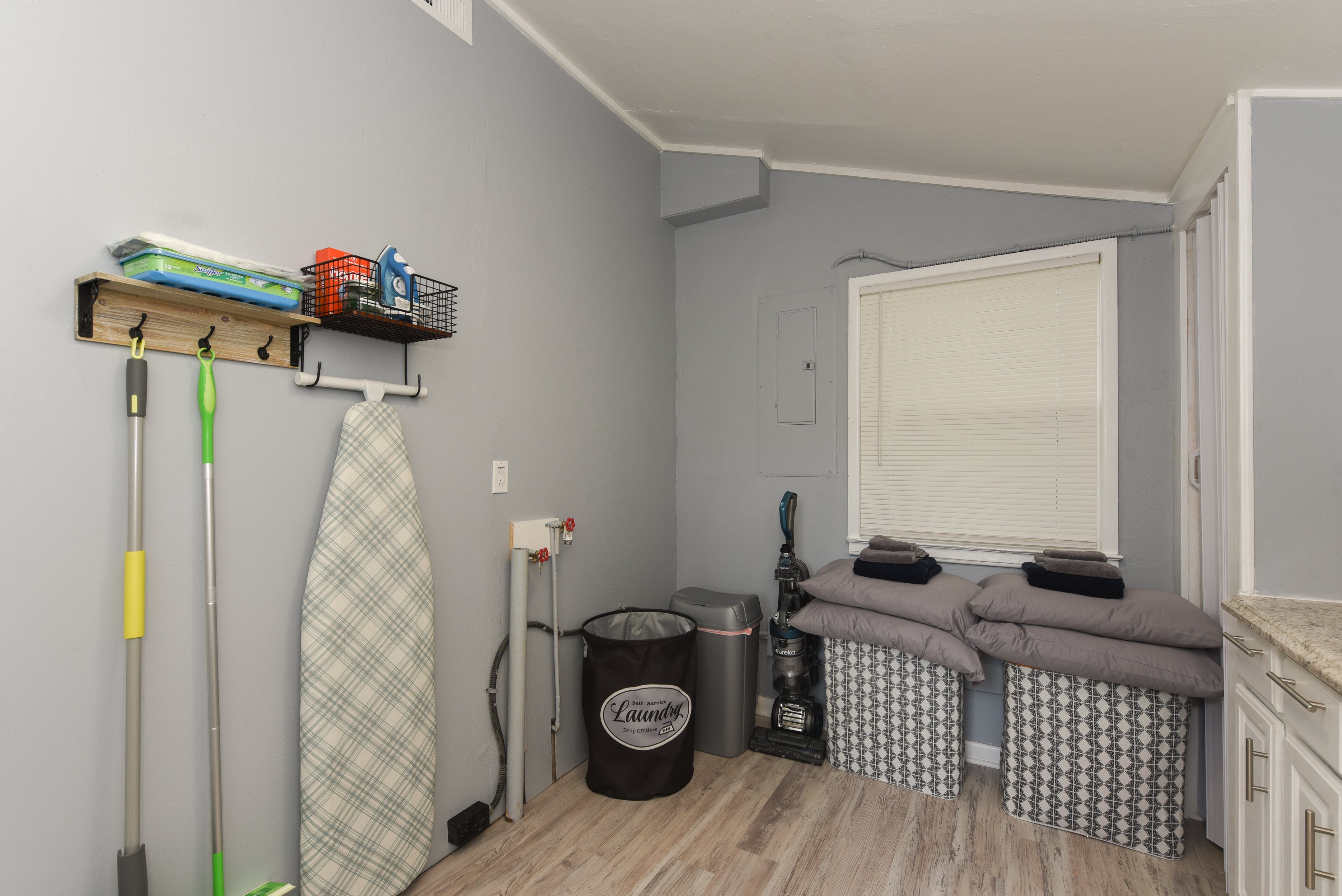 Laundry and storage area with cleaning supplies and shelving