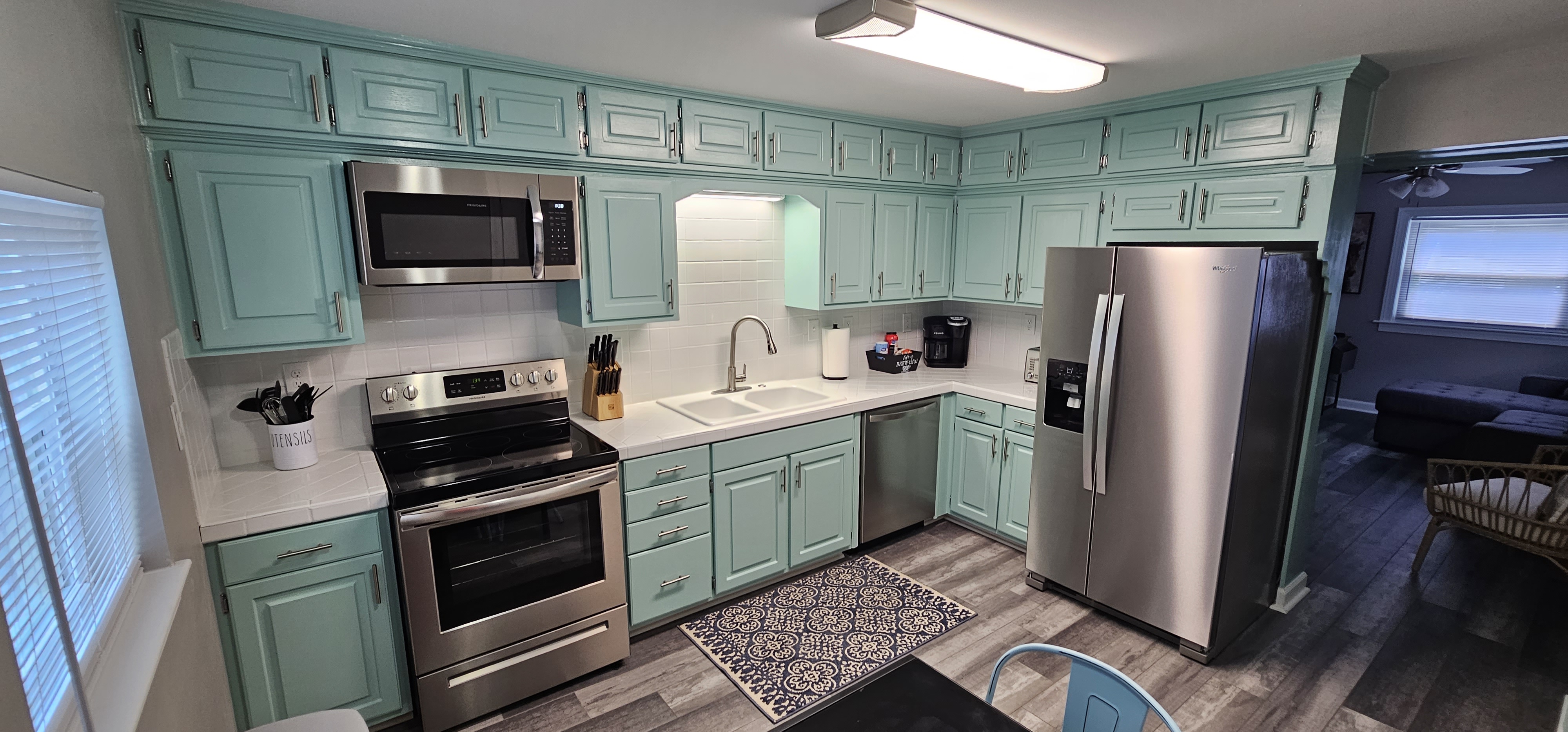 Spacious kitchen featuring teal cabinets and a dining area with metal chairs