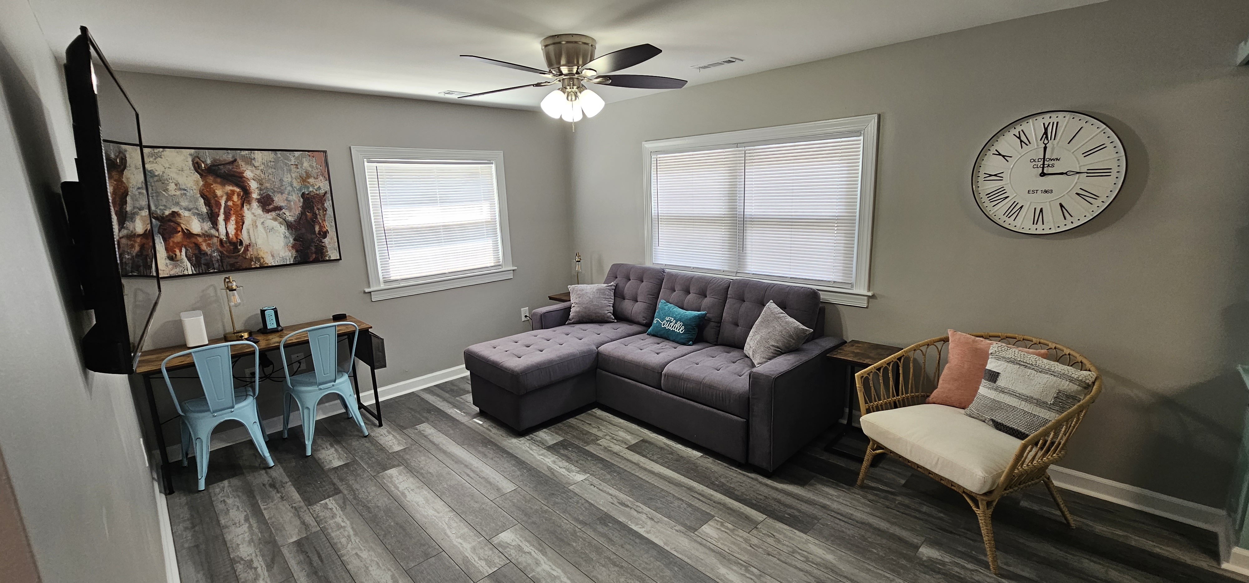 Living room with a large wall clock, sectional couch, and rattan chair