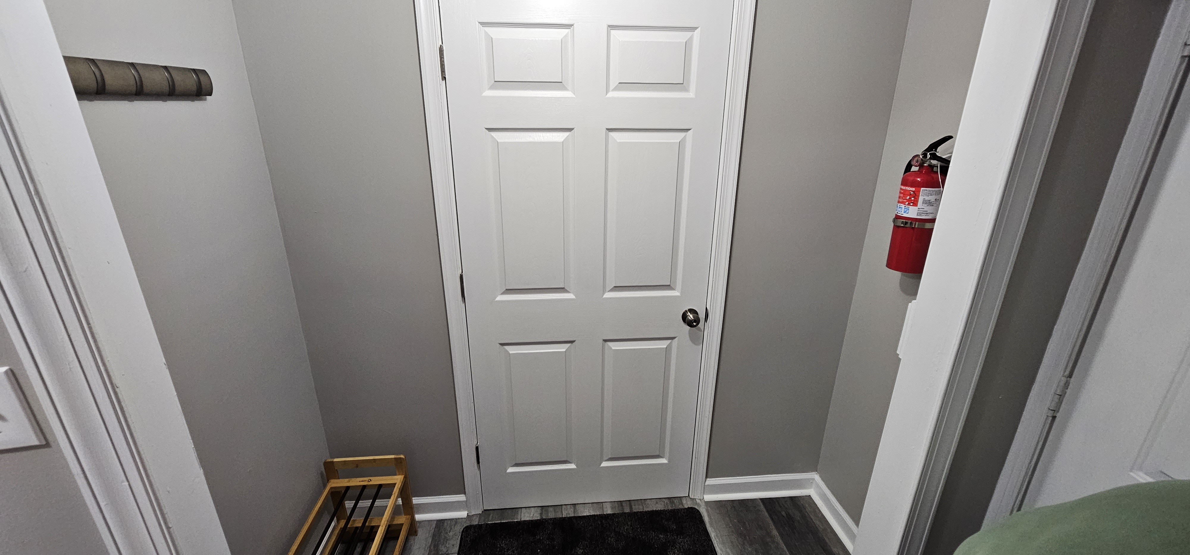 Entryway with a white door, fire extinguisher, and coat rack