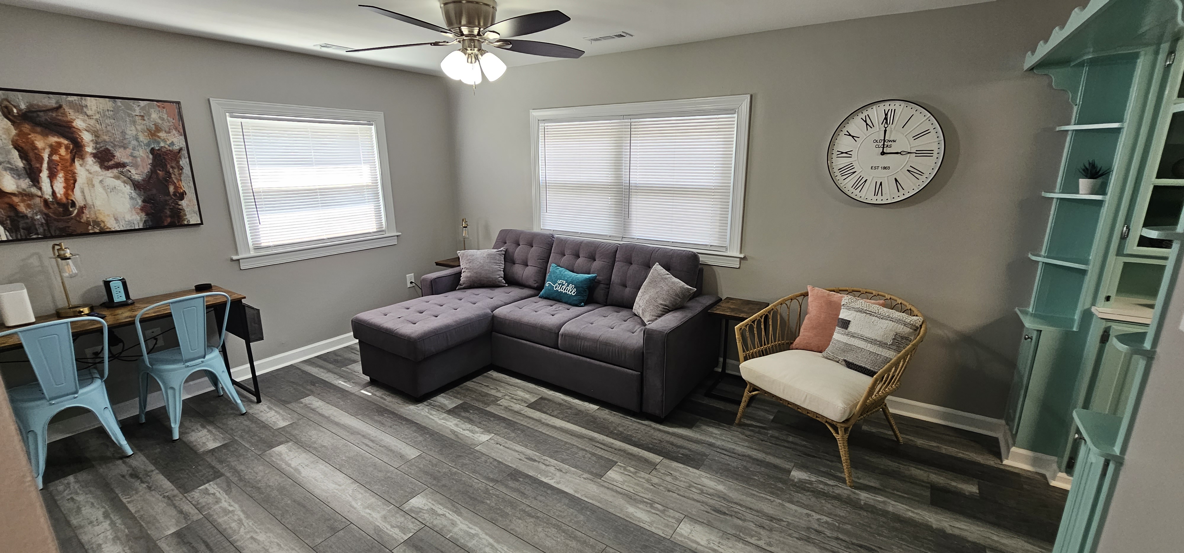 Living room with sectional sofa, office desk, and natural lighting