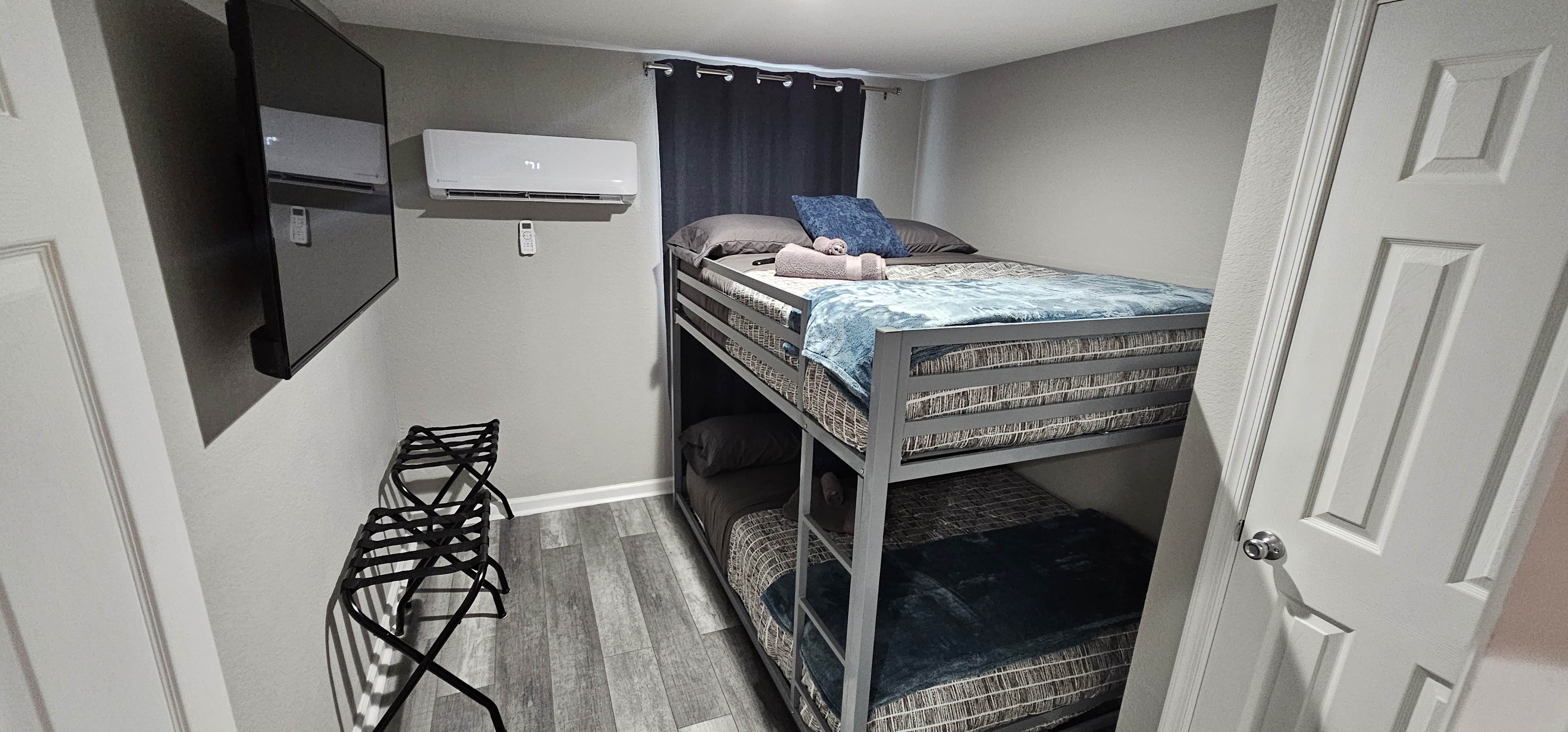 Cozy bedroom with bunk beds, a wall-mounted TV, and a luggage rack for guests.