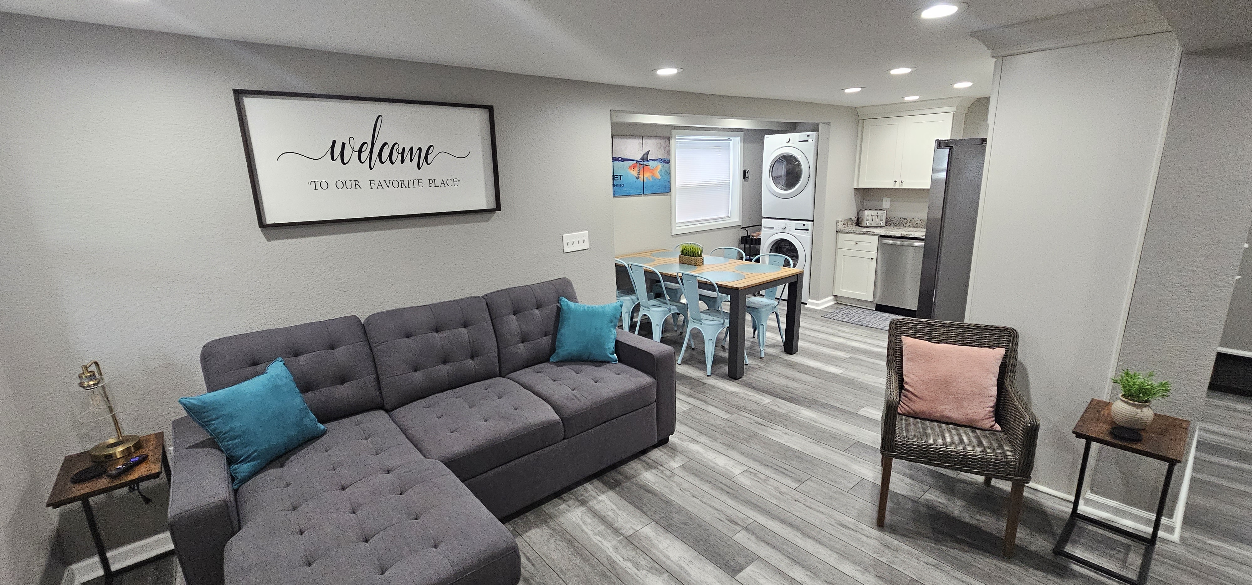 Modern living space with a sectional sofa, dining table, and stacked washer-dryer unit.