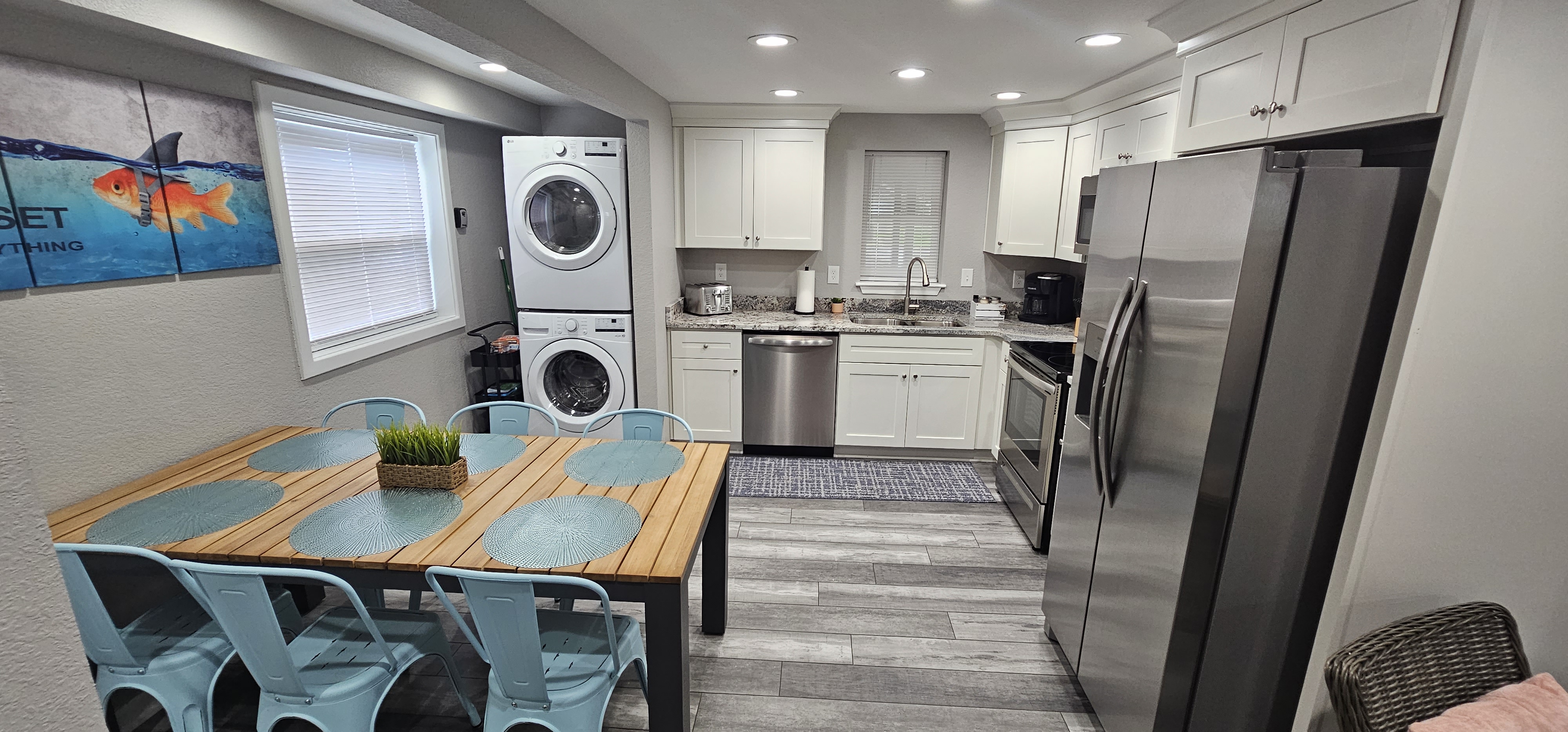 Bright and open kitchen with white cabinets, stainless steel appliances, and a stacked washer-dryer.