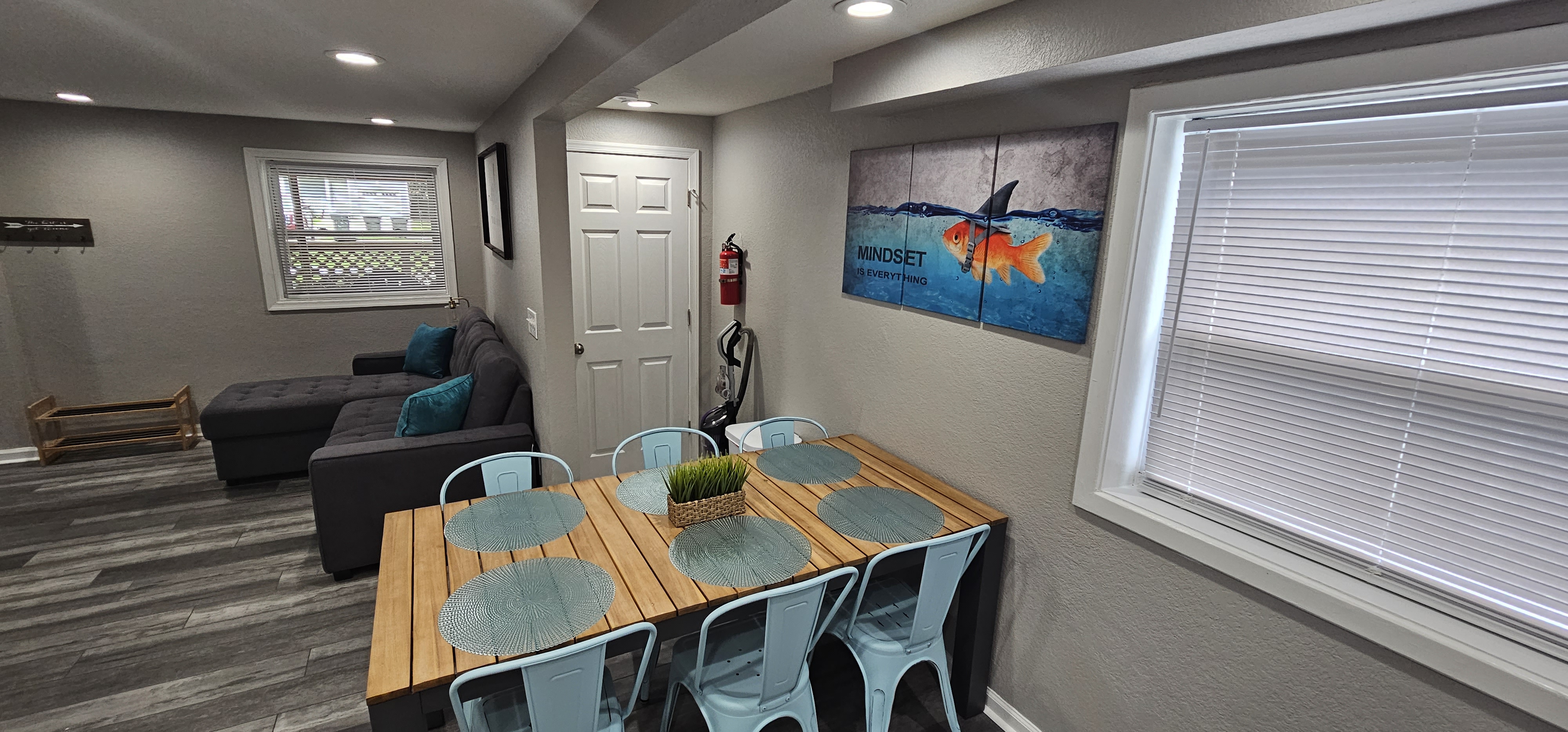 Another view of the dining area and living space with a sectional couch and large windows.
