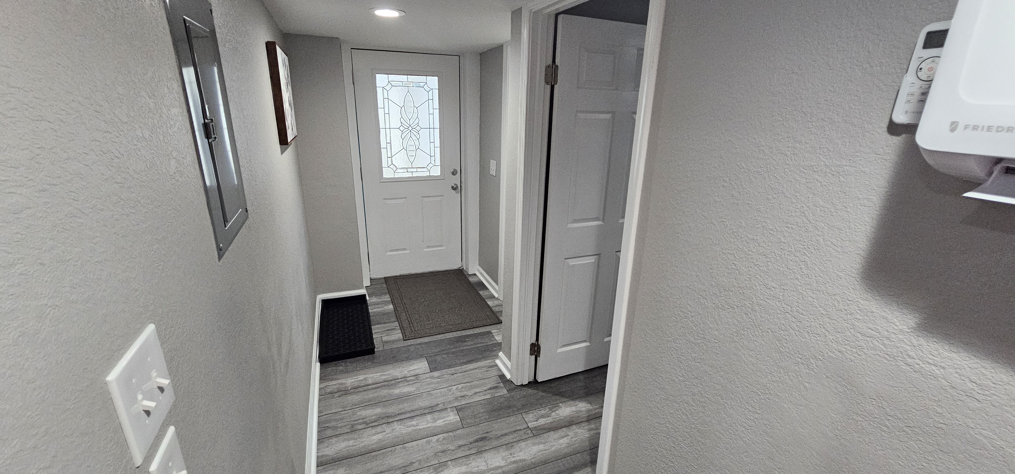 Hallway leading to the entrance door with a decorative glass window and a neatly arranged interior.