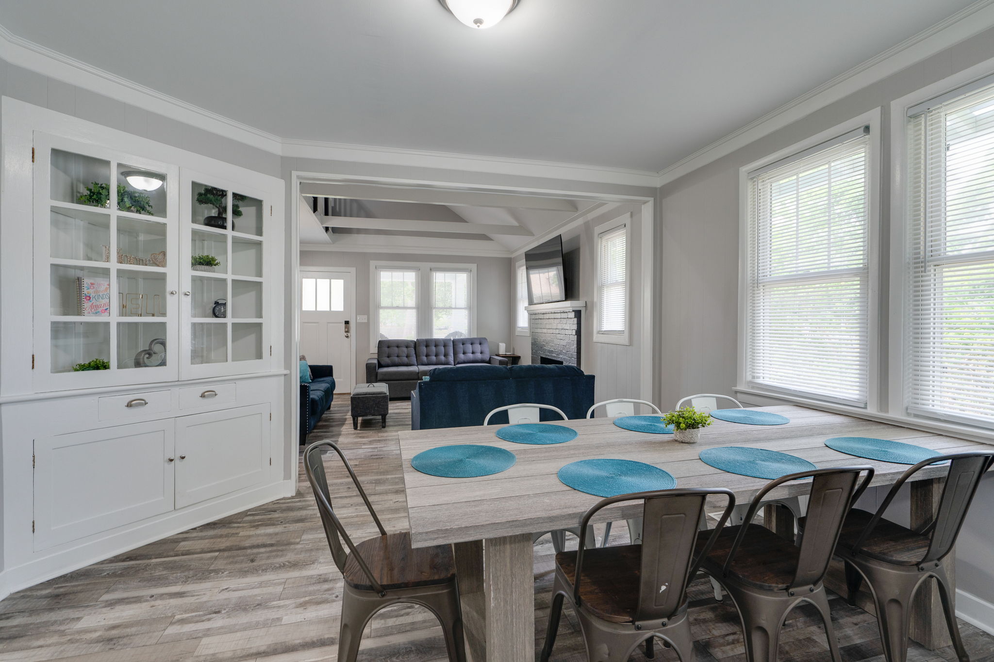 Built-in cabinet in a stylish dining room with large windows and a rustic table.