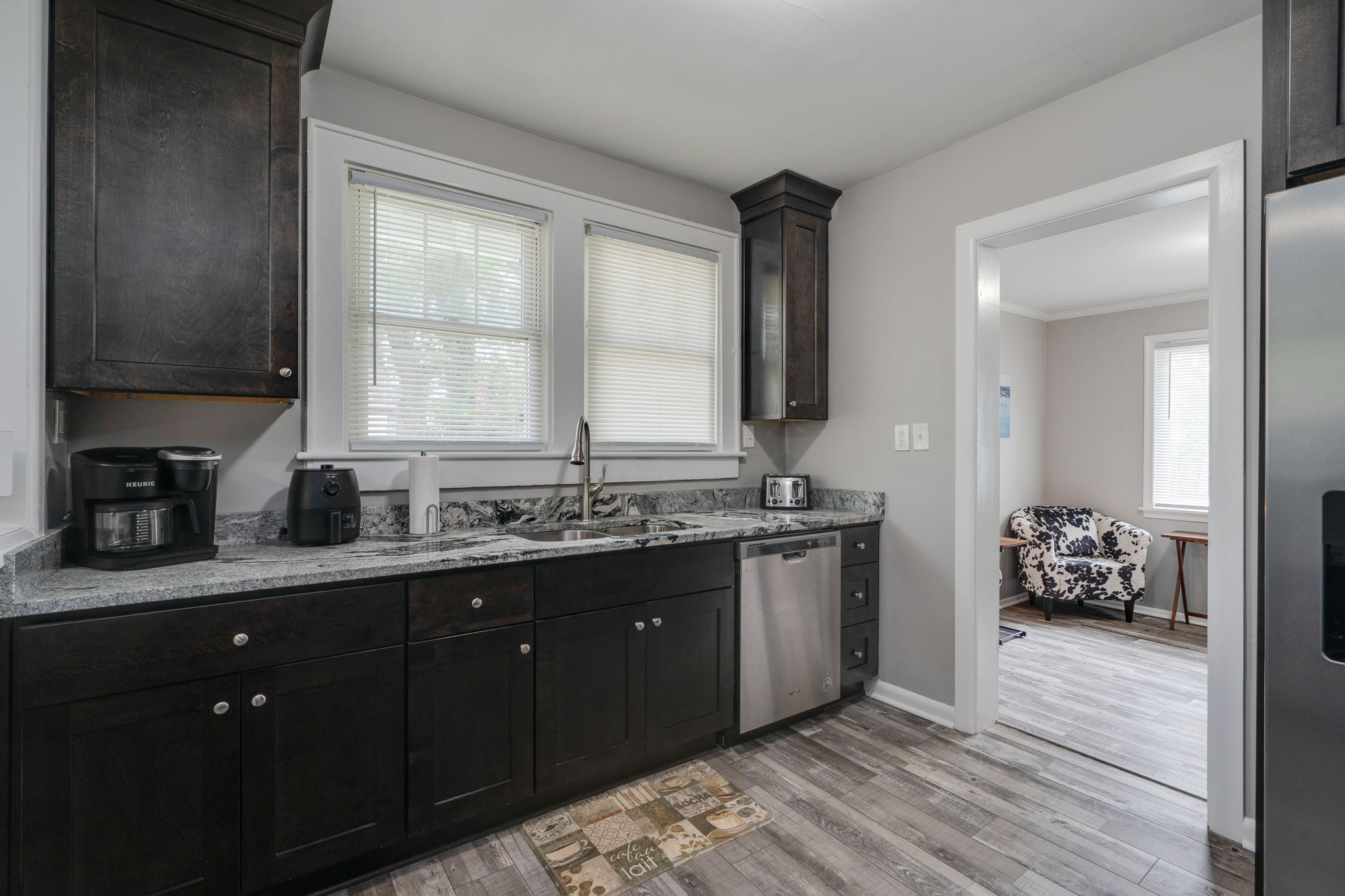 Modern kitchen with dark cabinets, stainless steel appliances, and marble countertops.