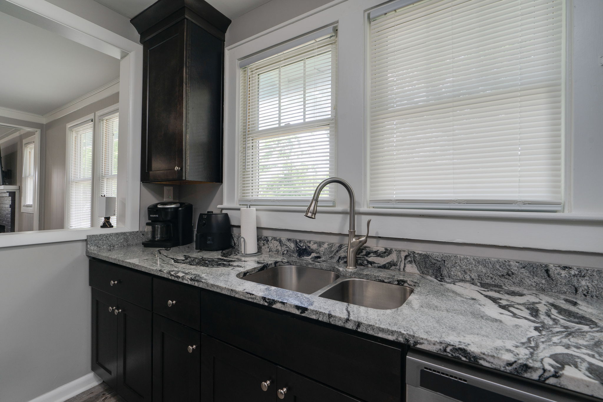 Close-up of a kitchen sink area with a double basin and elegant marble backsplash.