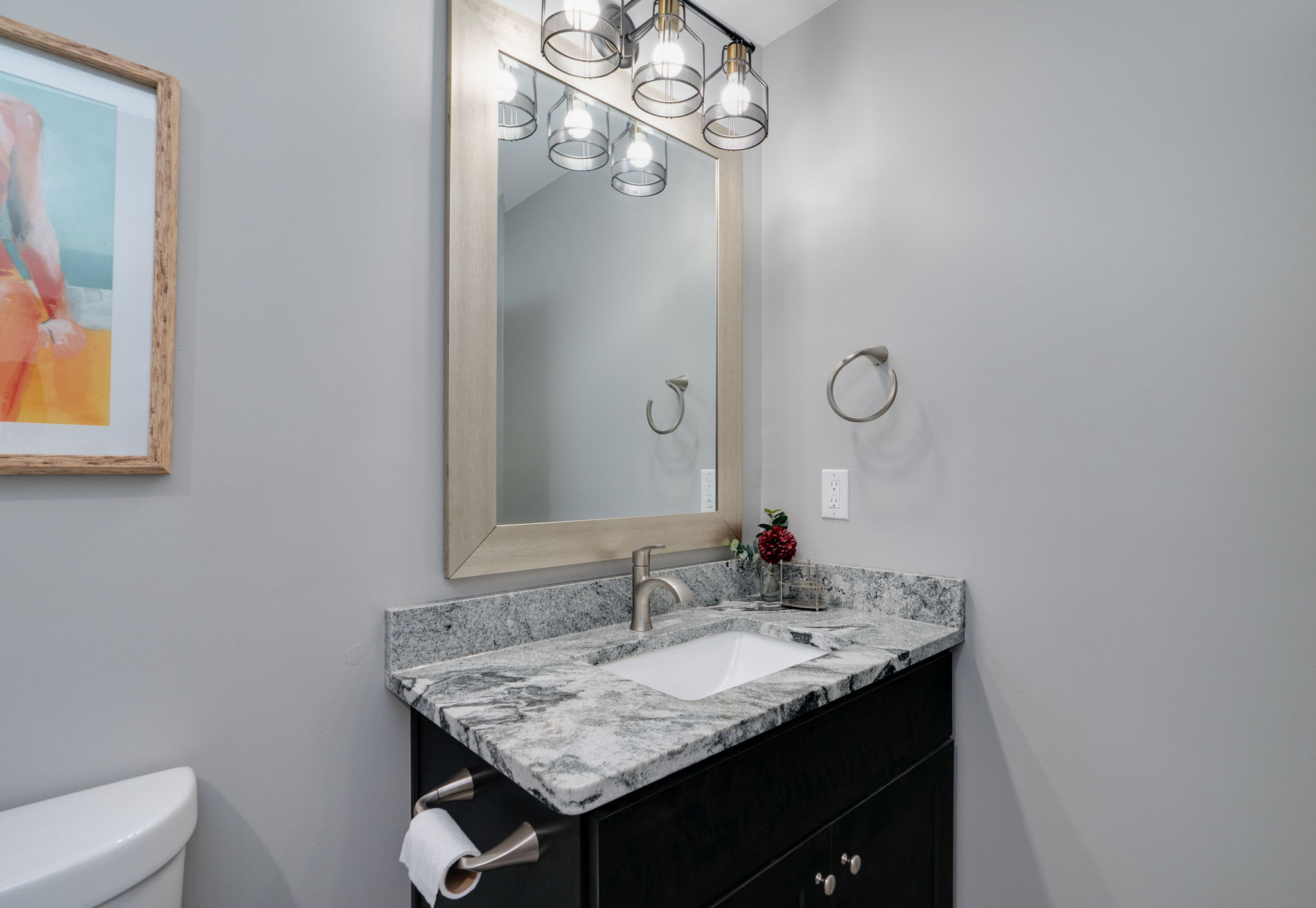 Elegant bathroom vanity with marble countertops, large mirror, and stylish lighting.
