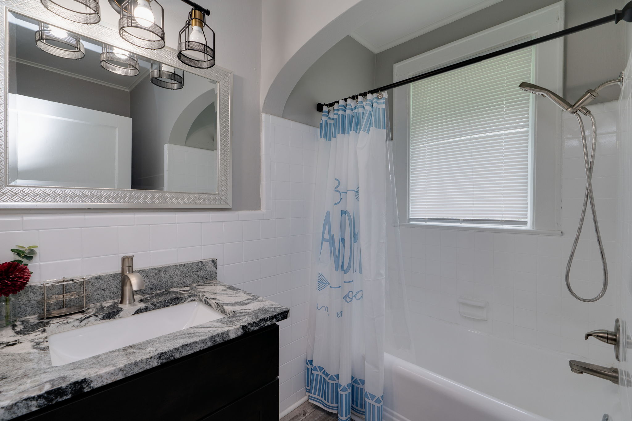 Bathroom with a shower/tub combo, marble vanity, and elegant mirror.
