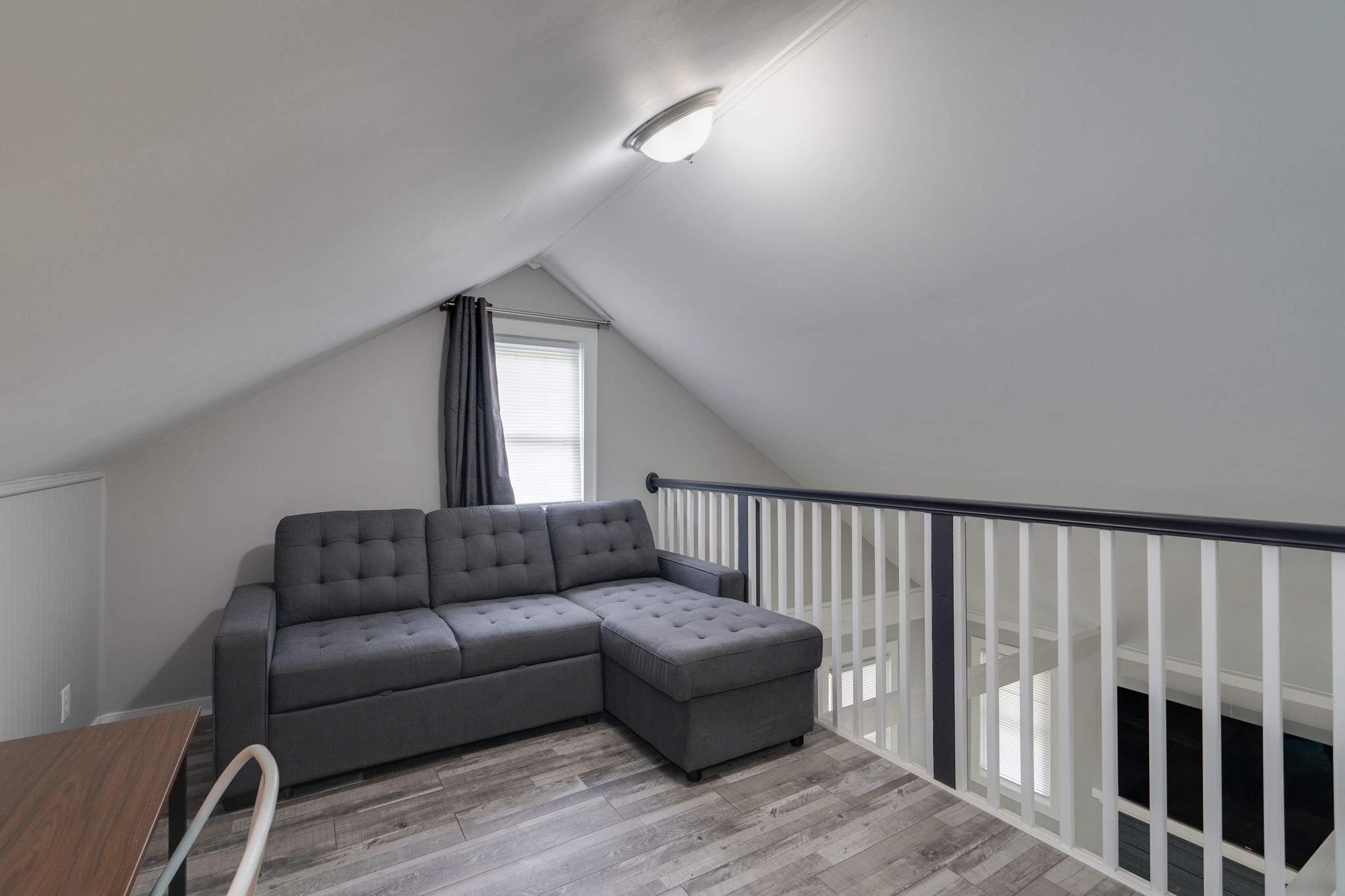 Loft seating area with a comfortable gray sectional and open railing.