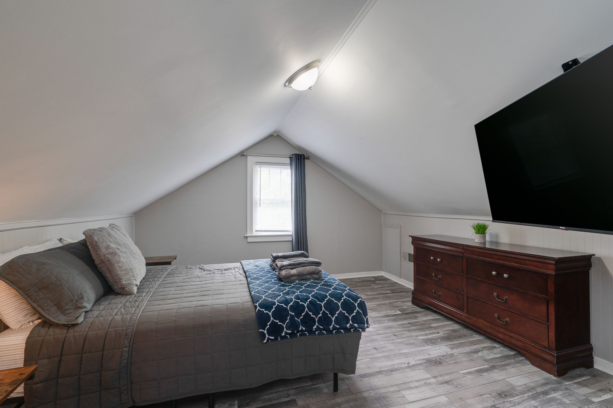 Third bedroom in the loft with a cozy bed and large wall-mounted TV.