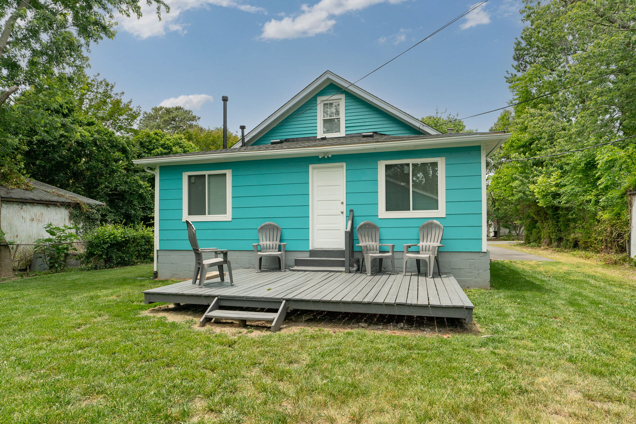 Rear view of the home showing the deck, backyard, and surrounding greenery.