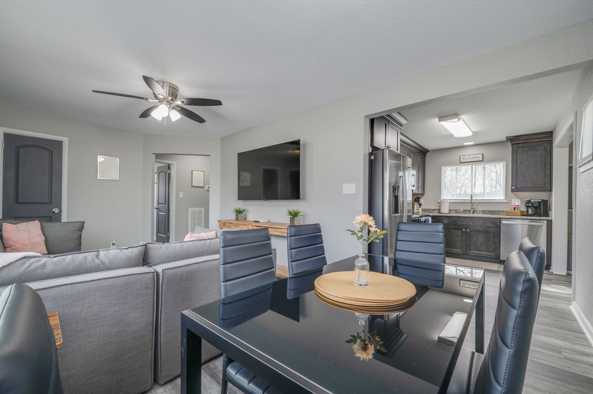 Dining area with black chairs and glass table near open kitchen