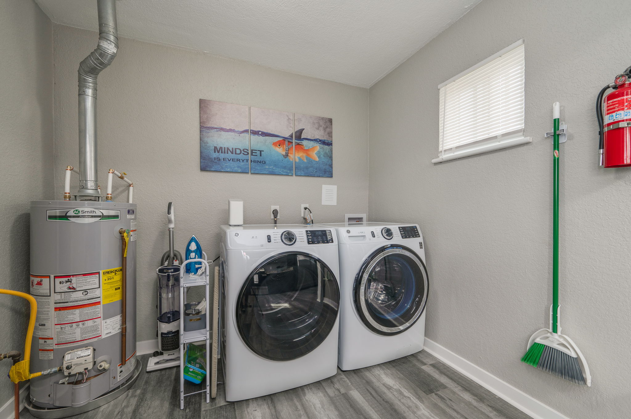 Laundry room with washer, dryer, water heater, and cleaning supplies
