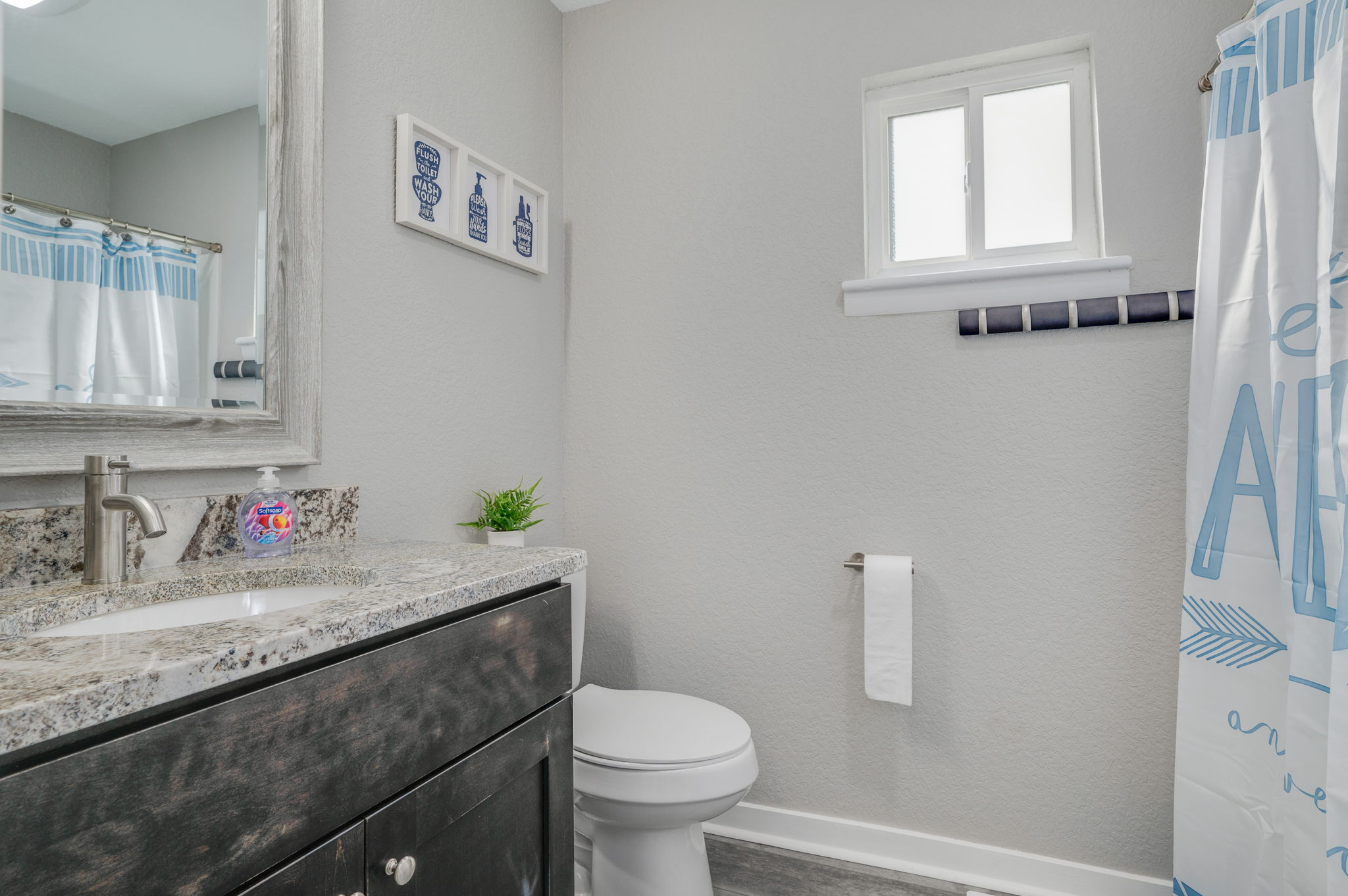 Modern bathroom with granite vanity, toilet, and blue-accented shower curtain