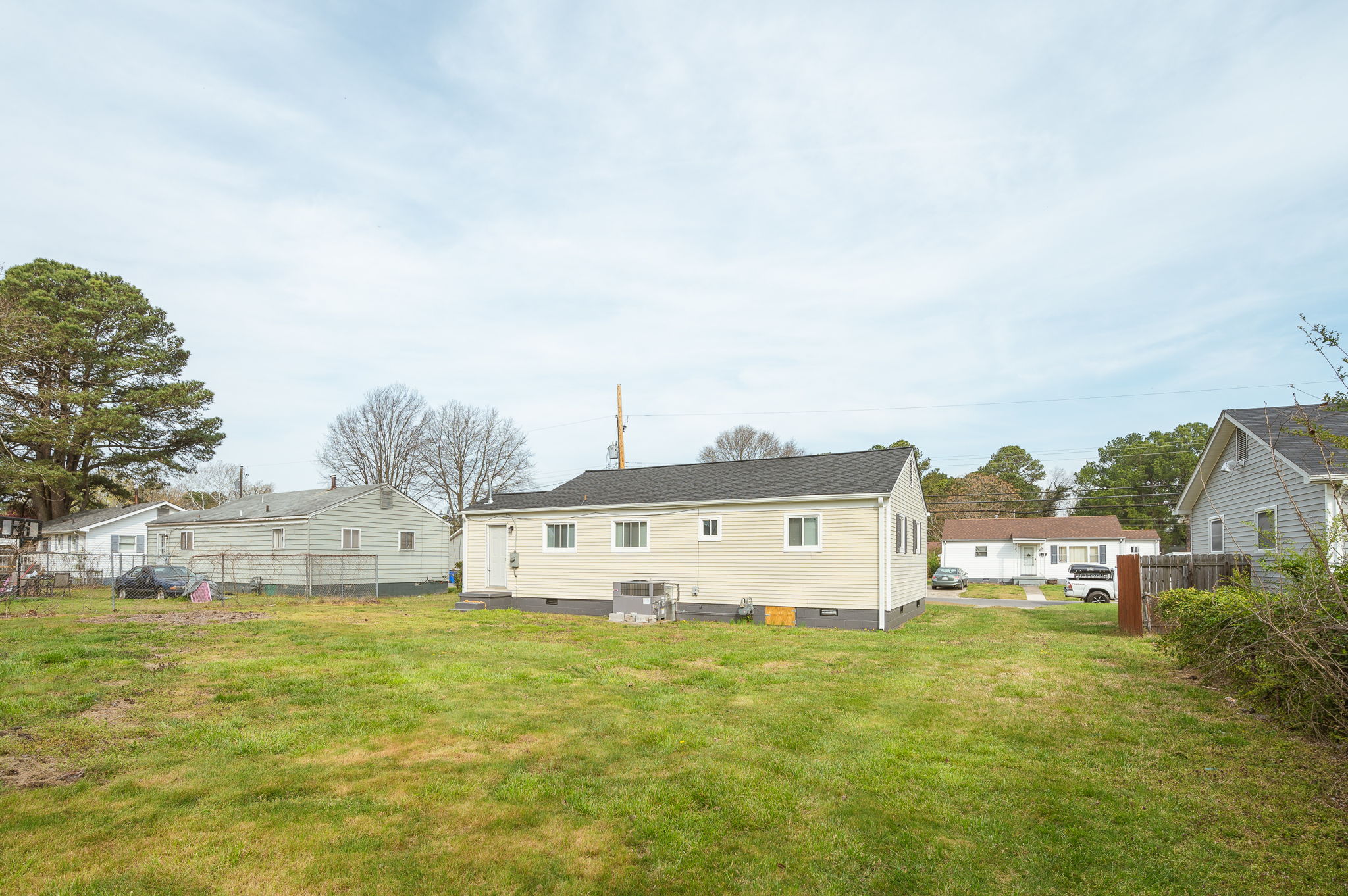Spacious backyard with green lawn and neighboring houses in the background