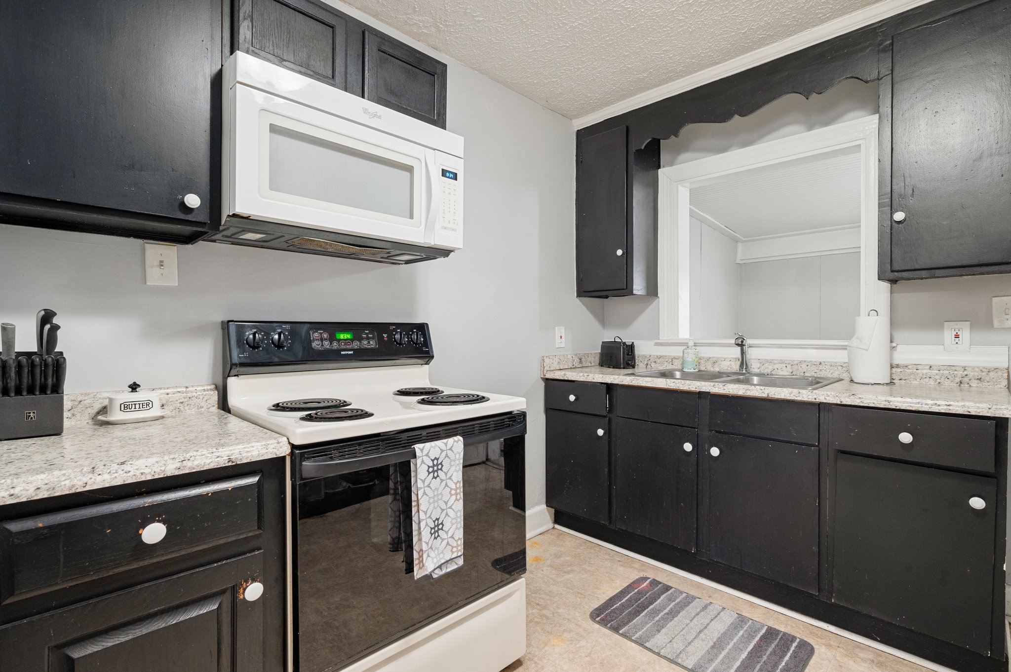 Close-up of kitchen featuring black cabinetry, with white appliances