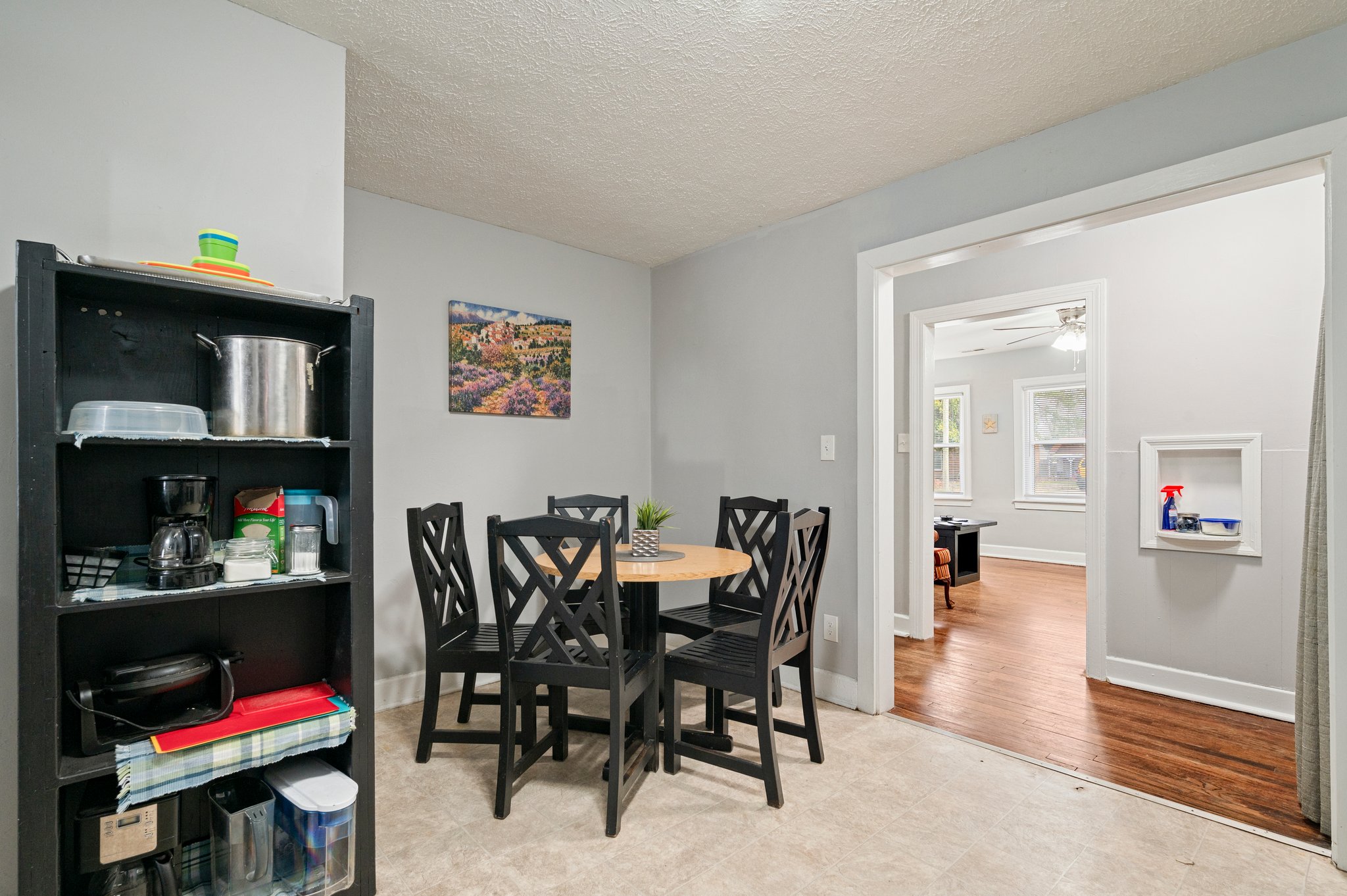 Dining area with black chairs, round wooden table, and open shelving unit.