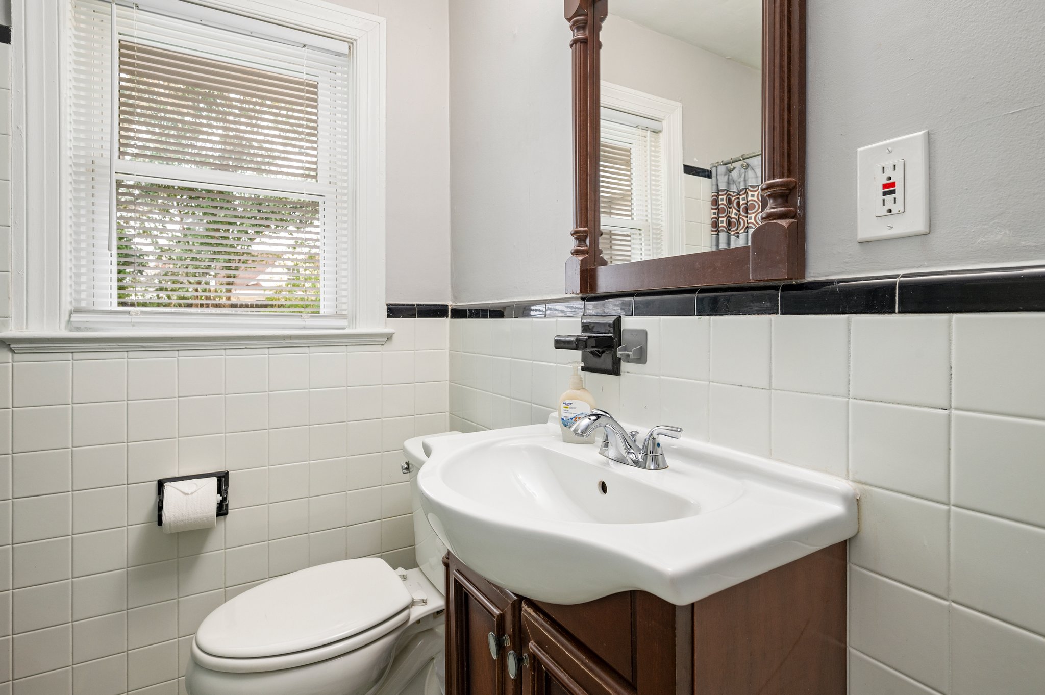 Close-up of bathroom vanity with sink, mirror, and white tiled walls.