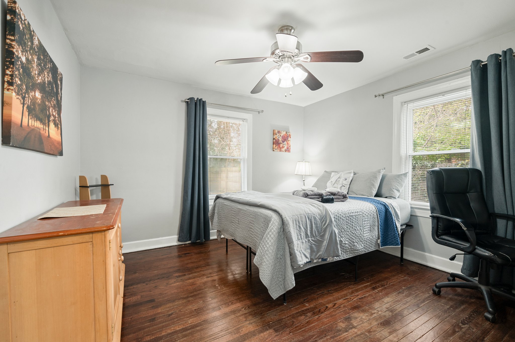Bedroom with a queen-sized bed, ceiling fan, and two large windows.