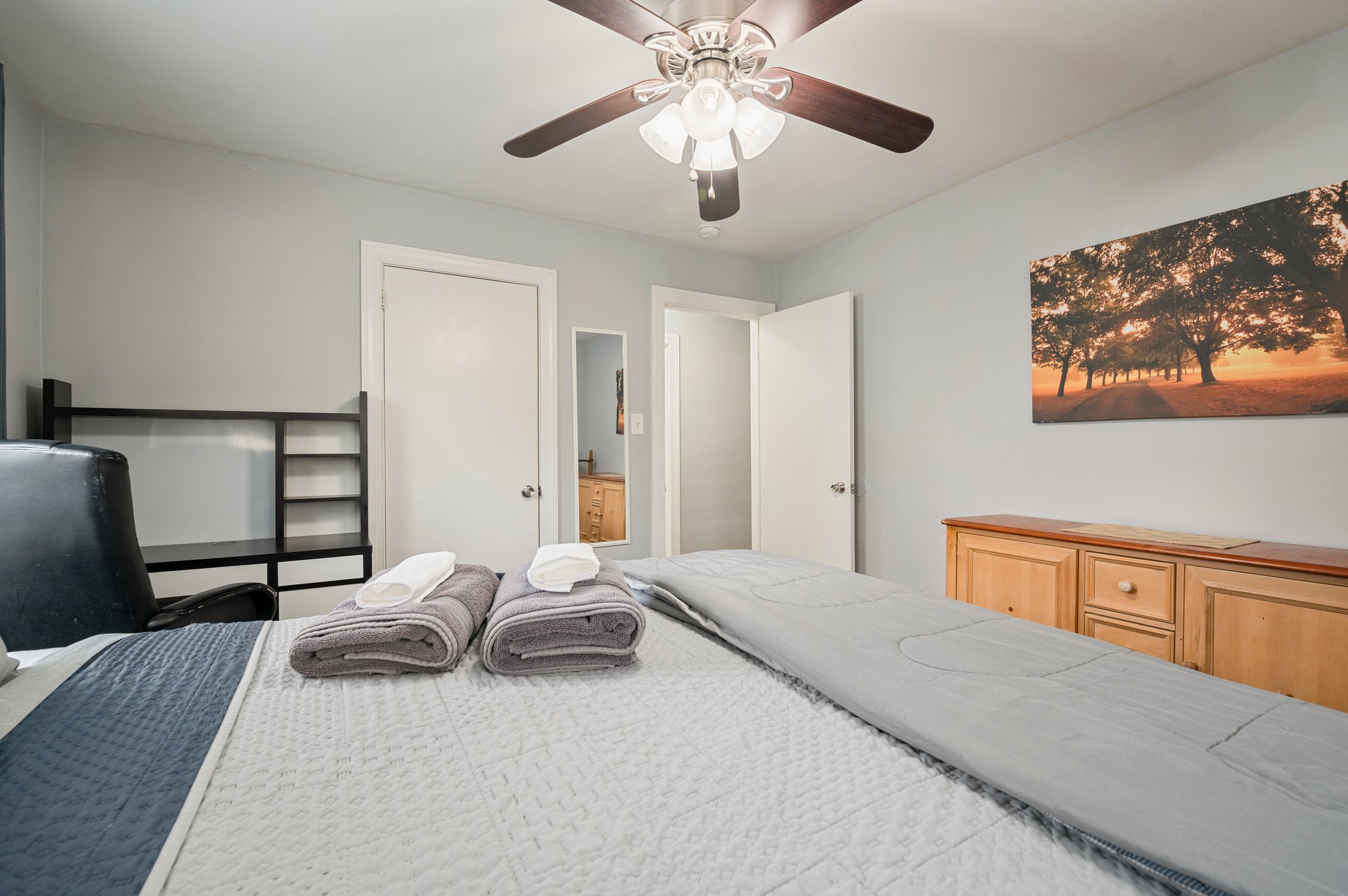 Close-up view of a neatly made bed with towels on top in a spacious bedroom.