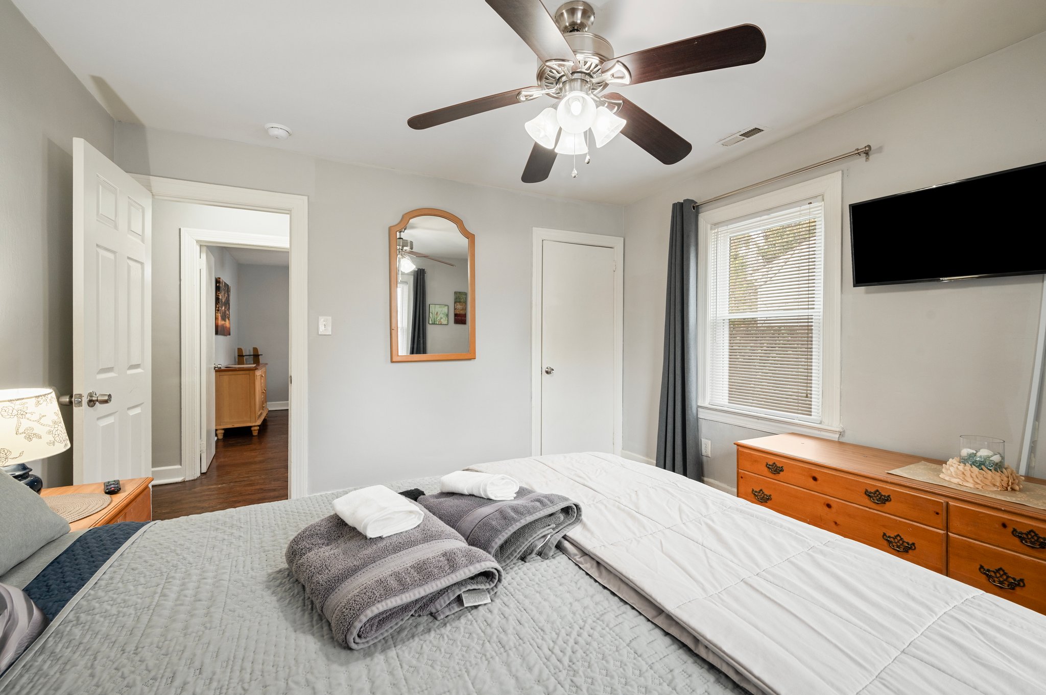 Bedroom with a bed, mirror, ceiling fan, and wooden dresser.