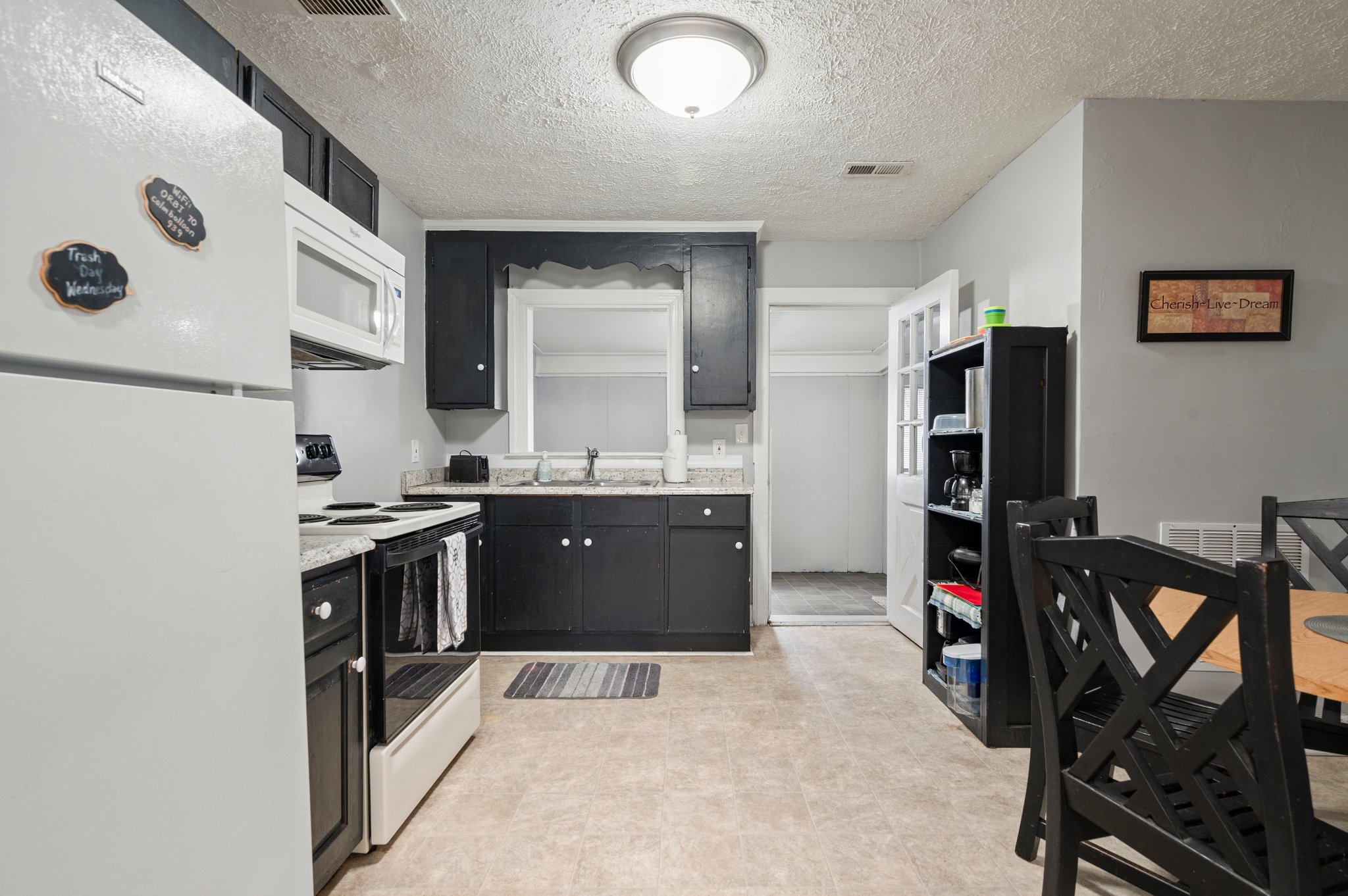 Full kitchen with dining area, black cabinets, and white appliances.