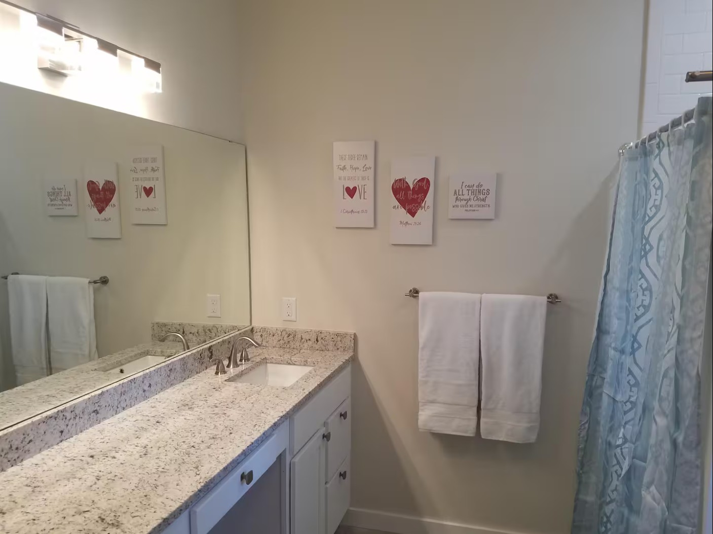 Bright bathroom with double vanity, granite countertop, and wall art