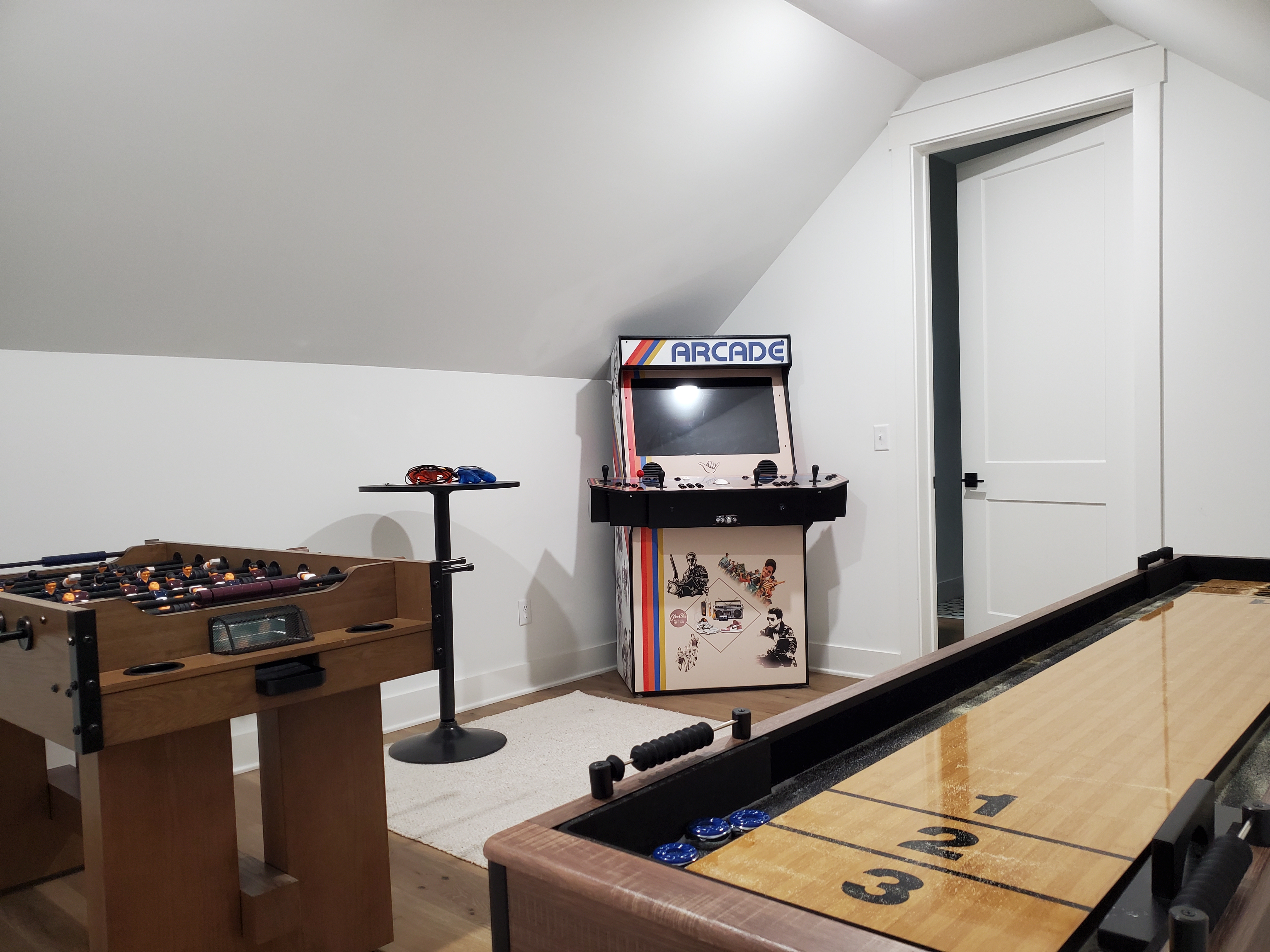 Game area with classic arcade machine, shuffleboard, and foosball