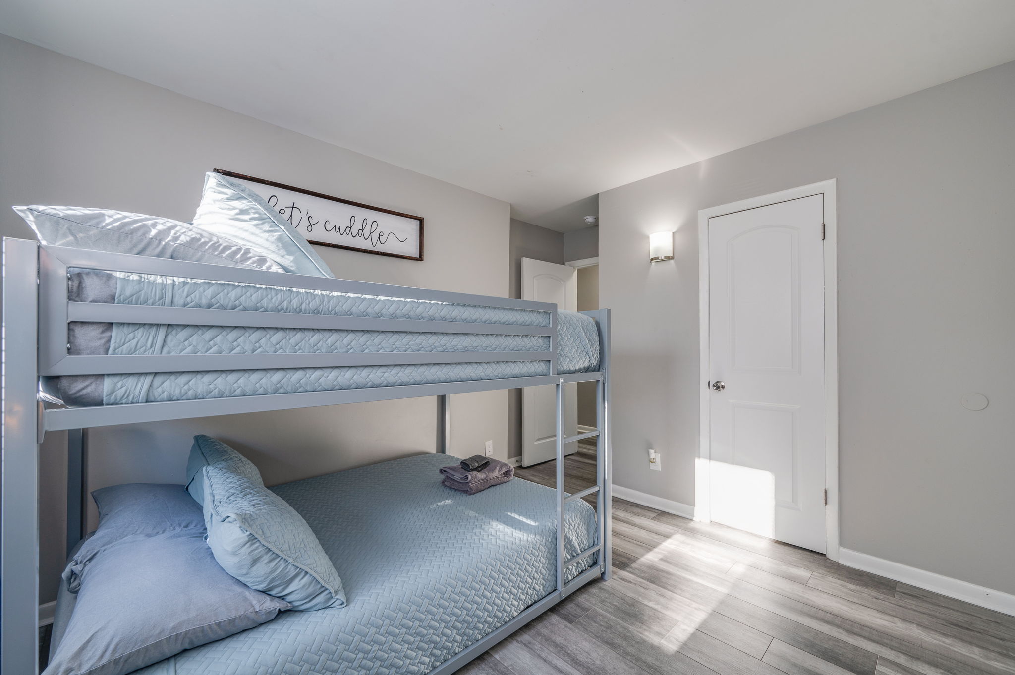 Another angle of the bedroom with light blue bunk bed, pillows, and towels neatly placed.